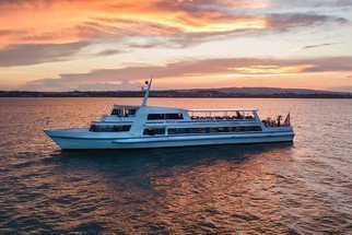 Schiff auf dem See mit orangem Abendhimmel