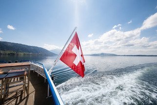 Schweizerfahne am Heck des Schiffes mit Blick über den See