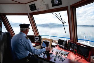 Schiffsführer fahrend in Kabine mit Blick auf den See