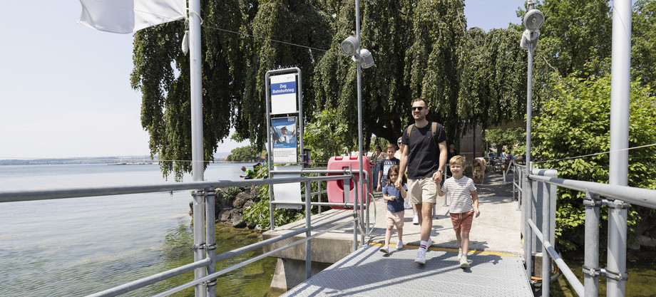 Vater hält seine beiden Kinder an der Hand und geht auf dem Steg