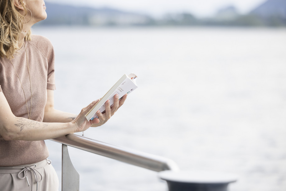 Hygge Zeit auf dem Schiff - Frau lesend an Reling